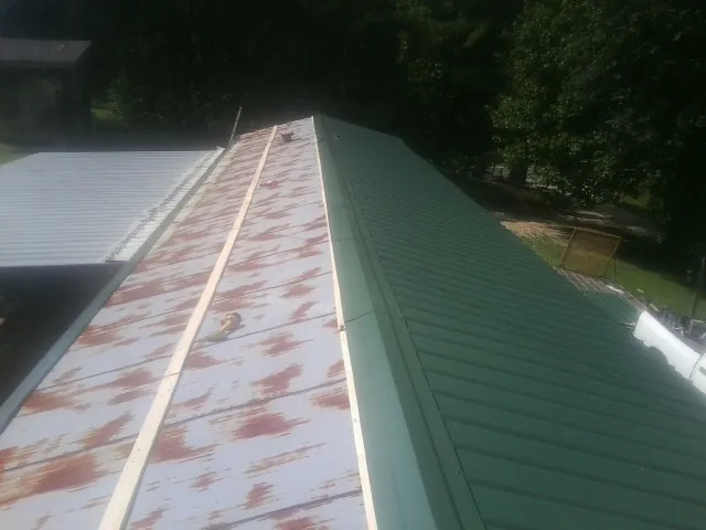 Old rusted panels beside newly installed green metal roofing — Wind Damage Roof Repair by Roofing Brothers in Bayville