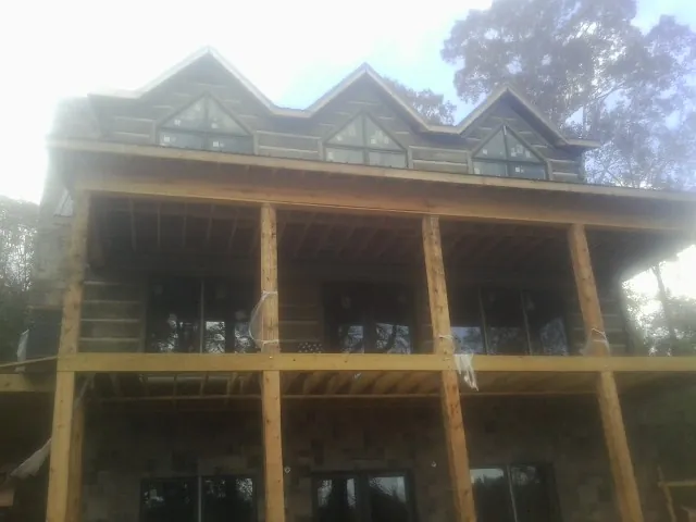Dormers and porch framing on a large log home under construction — Roof Coating work by our crew in Bayville