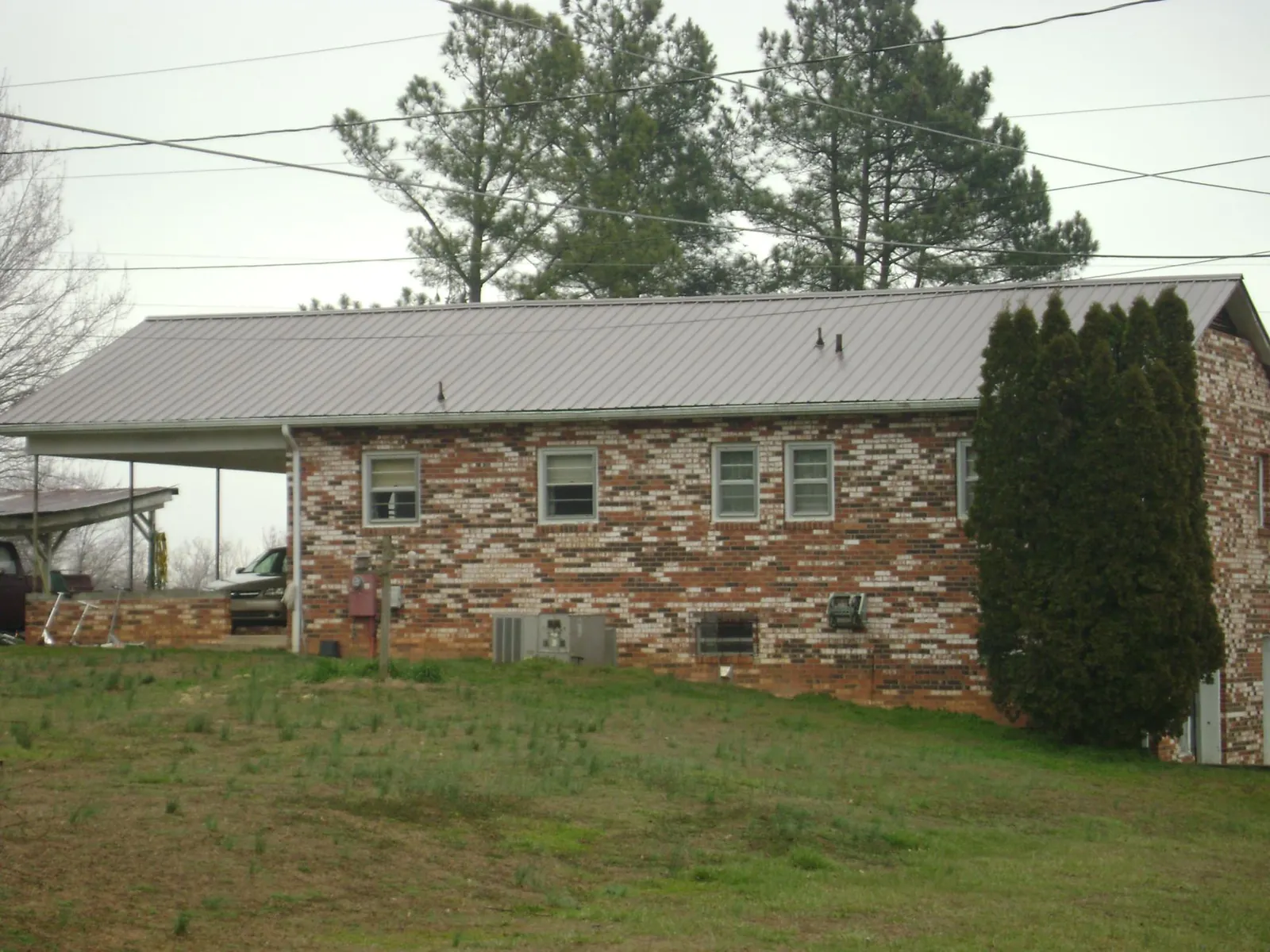 Gray metal roof on a brick split level home with a carport in Bayville