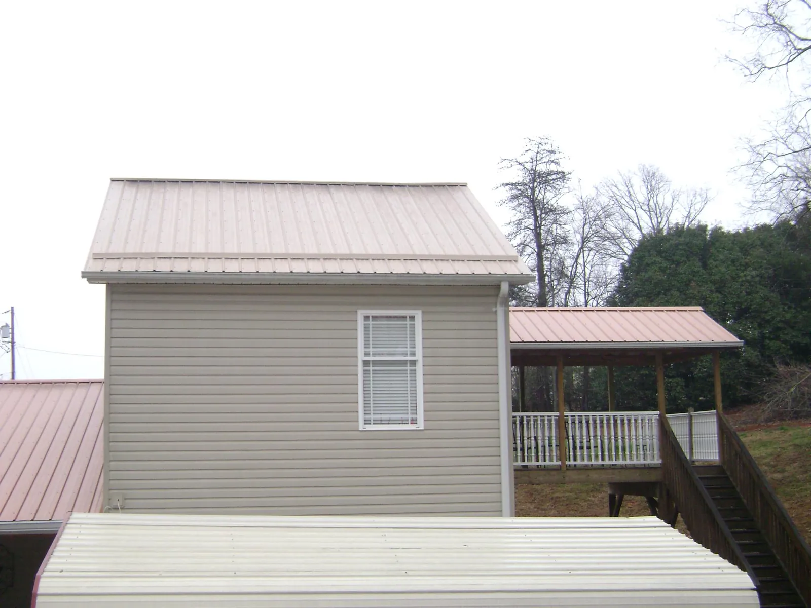 Tan metal roofs on a two story addition and attached porch, from a Roof Replacement job in Bayville