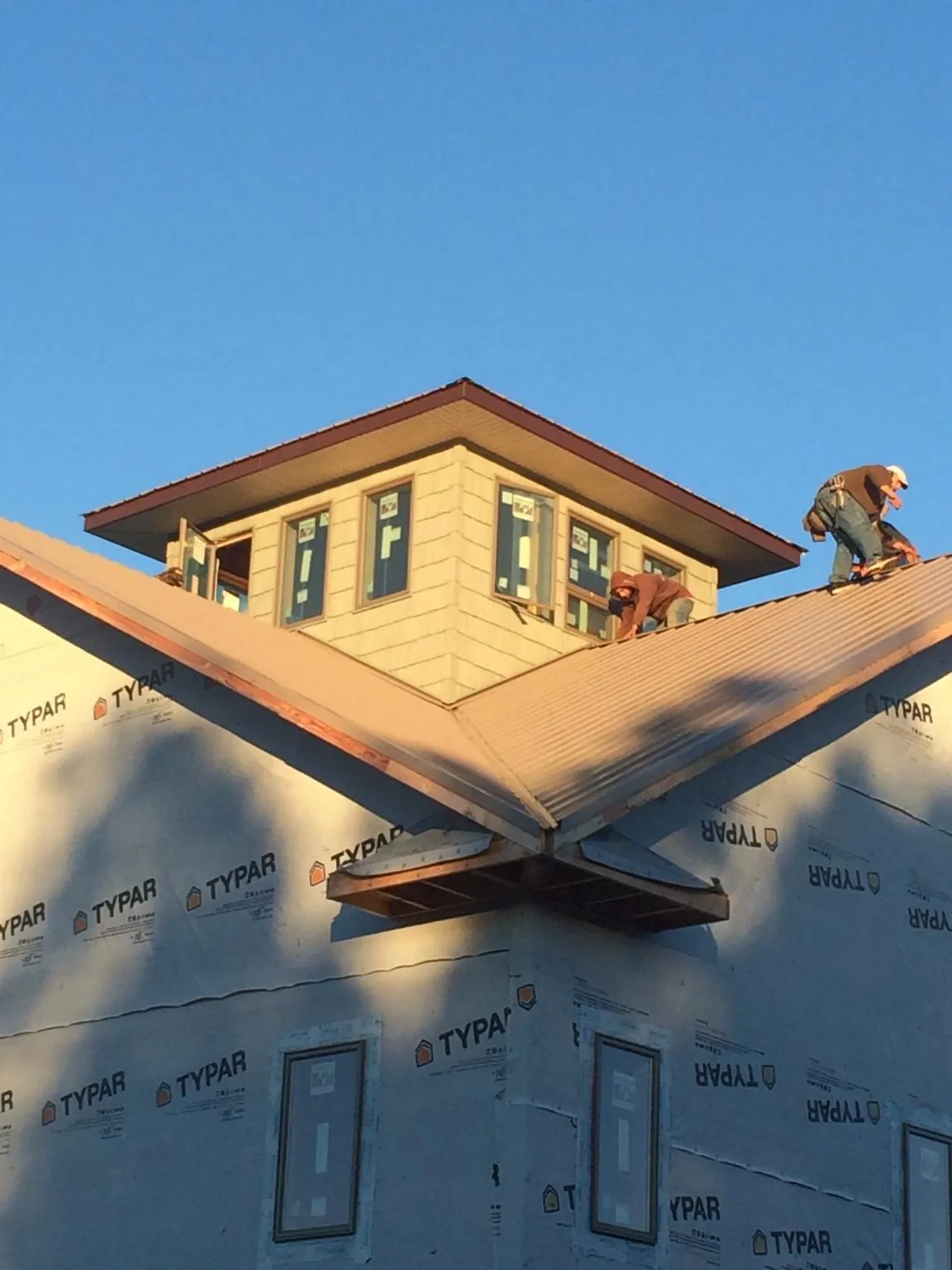 Roofers working around a rooftop cupola on a new metal roof at sunset — Roof Waterproofing in Bayville by Roofing Brothers